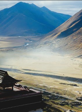 a hillside with a village and the square corner of a Chinese castle