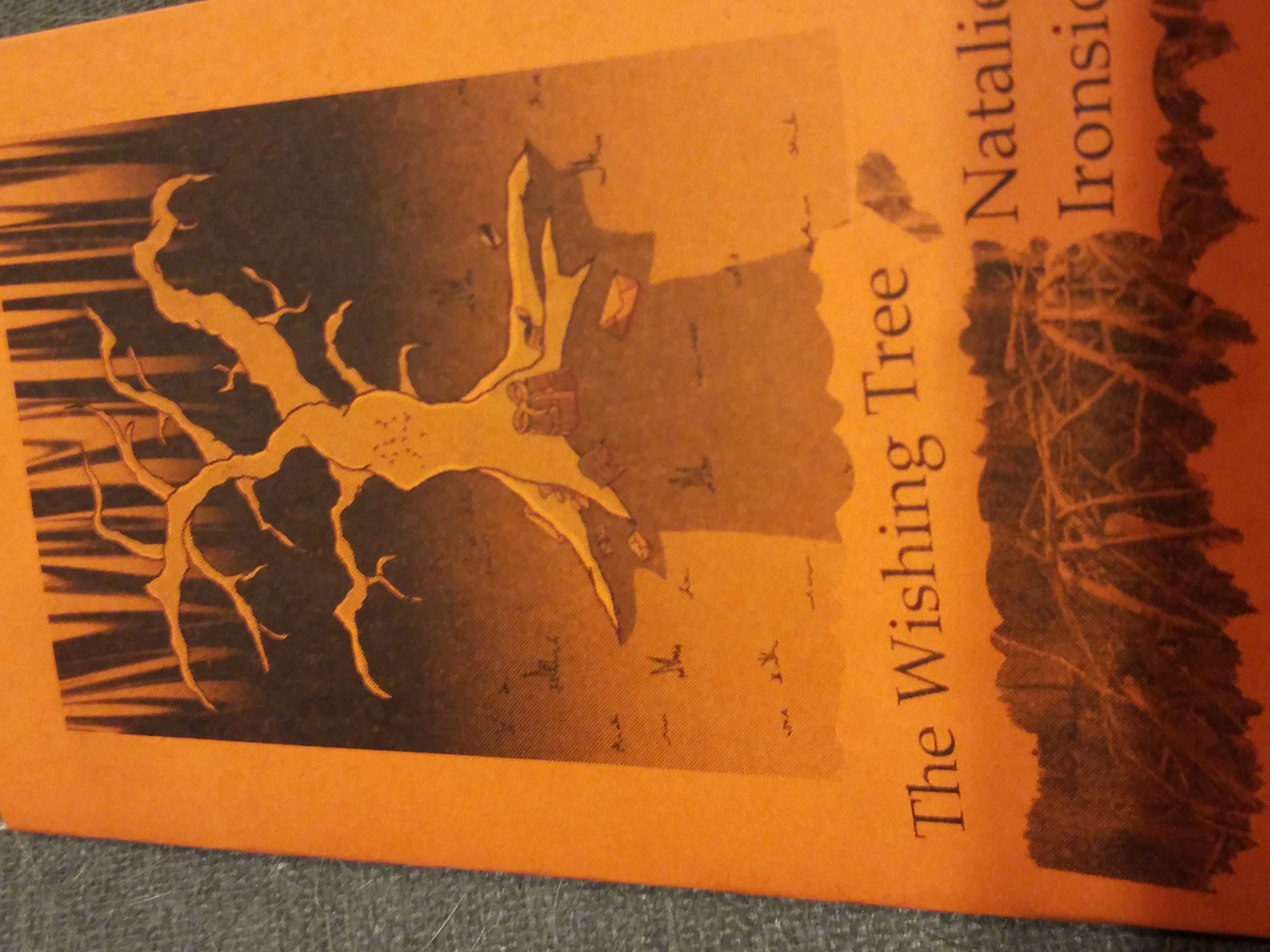 a zine in orange and black entitled “The Wishing Tree.” It features a grim looking tree with a present underneath, in shadow.